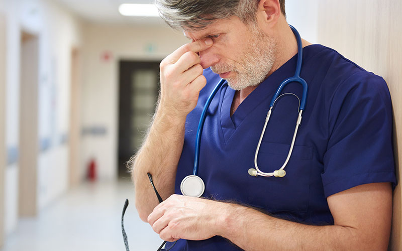 exhausted doctor, NHS under strain, overworked, low morale