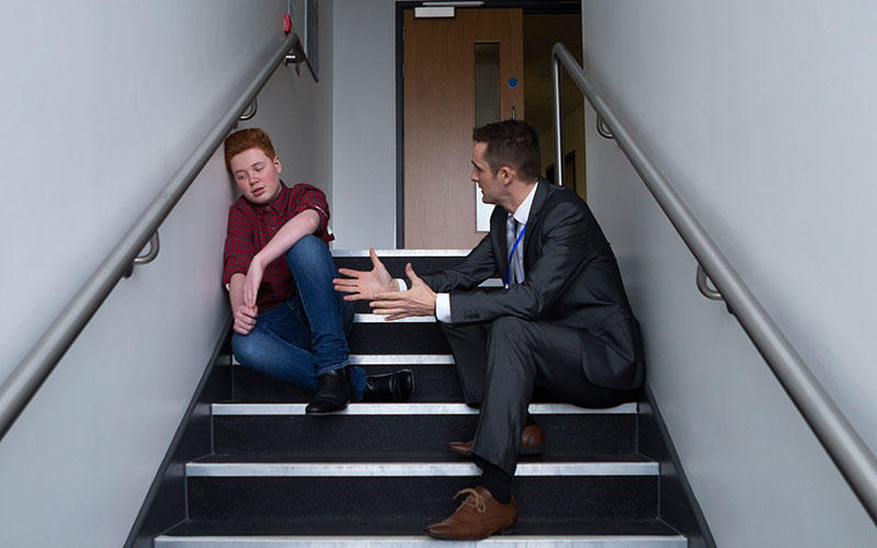teacher speaking to troubled student
