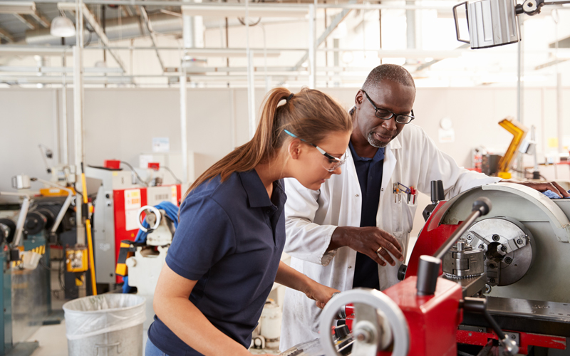 An engineering apprentice is shown how to use a machine ©Monkey Business Images, Shutterstock